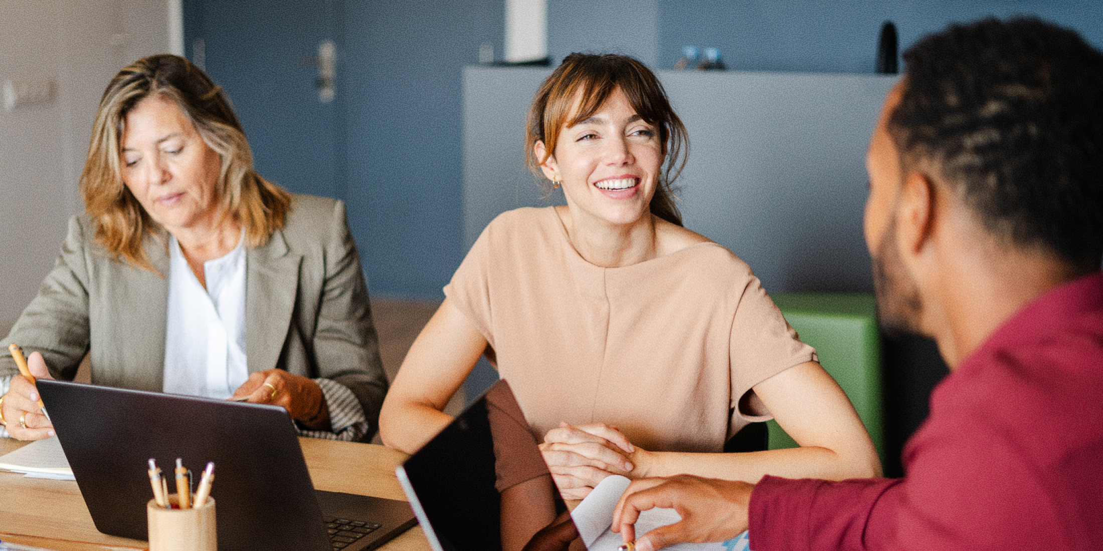 3 people sitting at a table talking.
